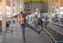 Un homme excité avec une valise se tient debout à une gare routière à Phuket, en Thaïlande, tenant une carte et attendant avec impatience un bus pour Bangkok.
