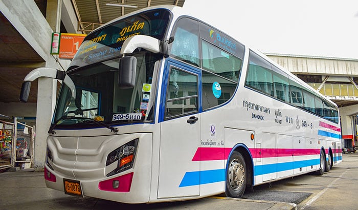 Un bus de la compagnie Sombat Tour stationné à la gare routière du Sud de Bangkok, arborant les caractéristiques bandes bleues et violettes, assurant la liaison entre Phuket et Bangkok.